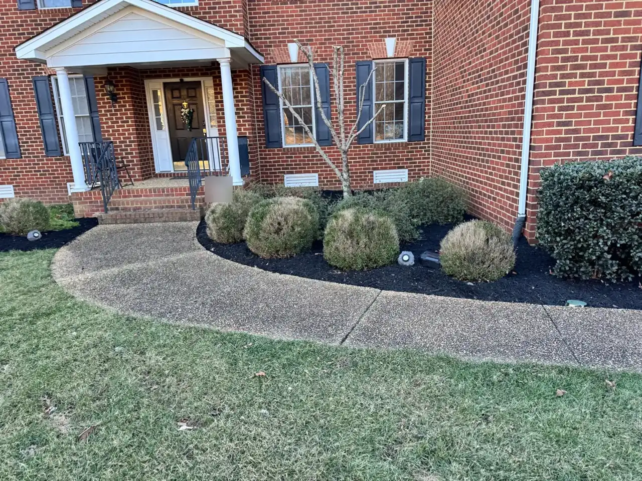 Black mulch bed along the front walk of a brick colonial home